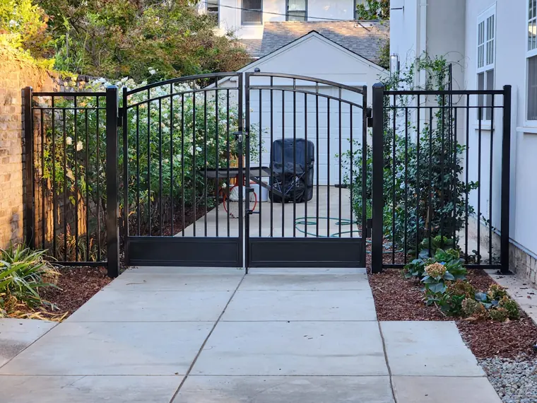Arched black iron driveway gates with side panels installed by Palmer Fence in the Sacramento area