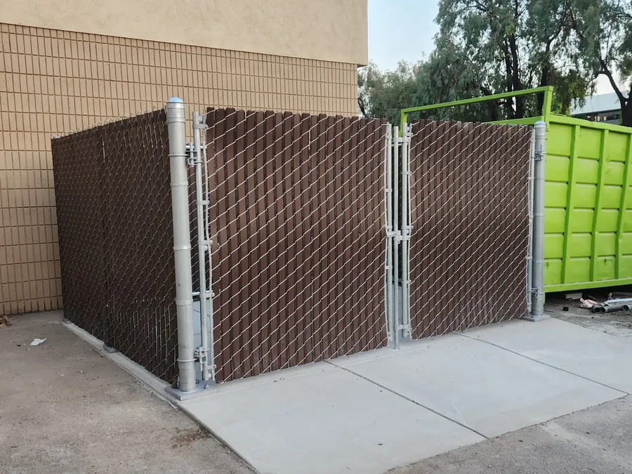 Chain-link dumpster enclosure with privacy slats and gates built by Palmer Fence in Roseville