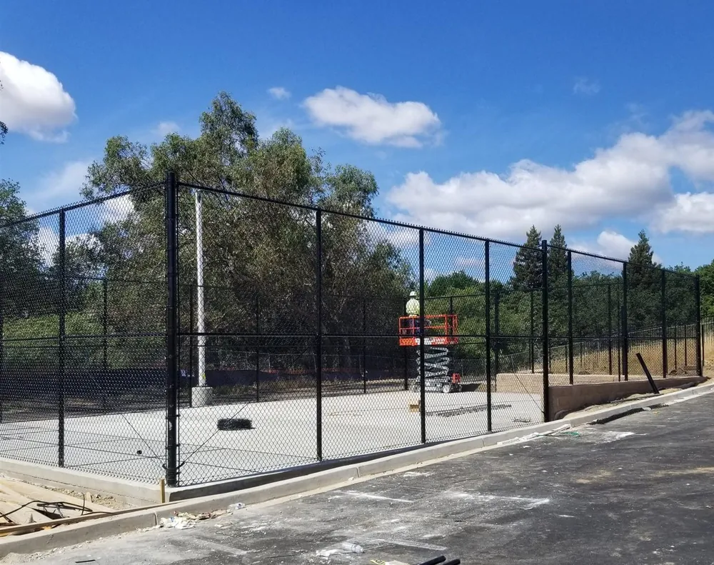 Tall black vinyl-coated commercial chain link fence around a sports court in the Sacramento area, installed by Palmer Fence