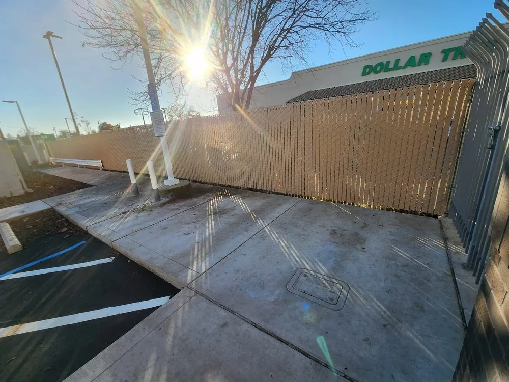 Commercial chain link fence with tan privacy slats screening a storefront service area by Palmer Fence