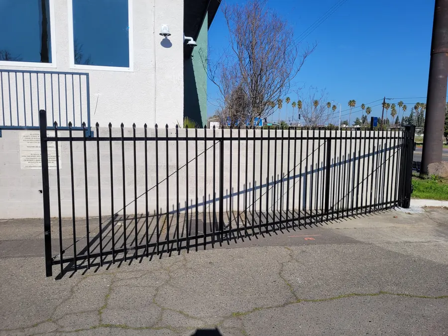 Black spear-top swing gate along a block wall, built by Palmer Fence in Sacramento