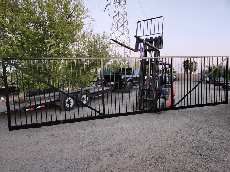Custom steel sliding gate being moved with a forklift at the Palmer Fence fabrication yard in Sacramento