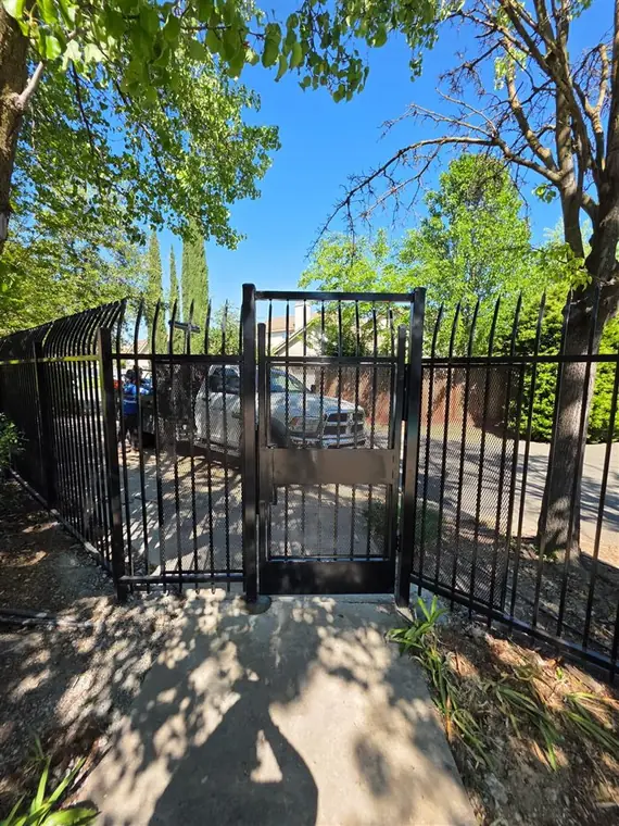 Black ornamental iron fence with a pedestrian gate in Elk Grove, by Palmer Fence
