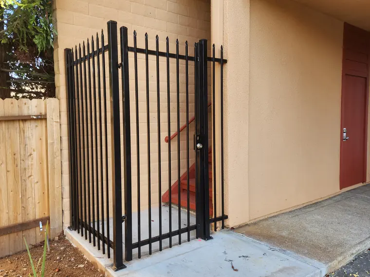 Black iron security gate enclosing an apartment stairwell in Sacramento, by Palmer Fence
