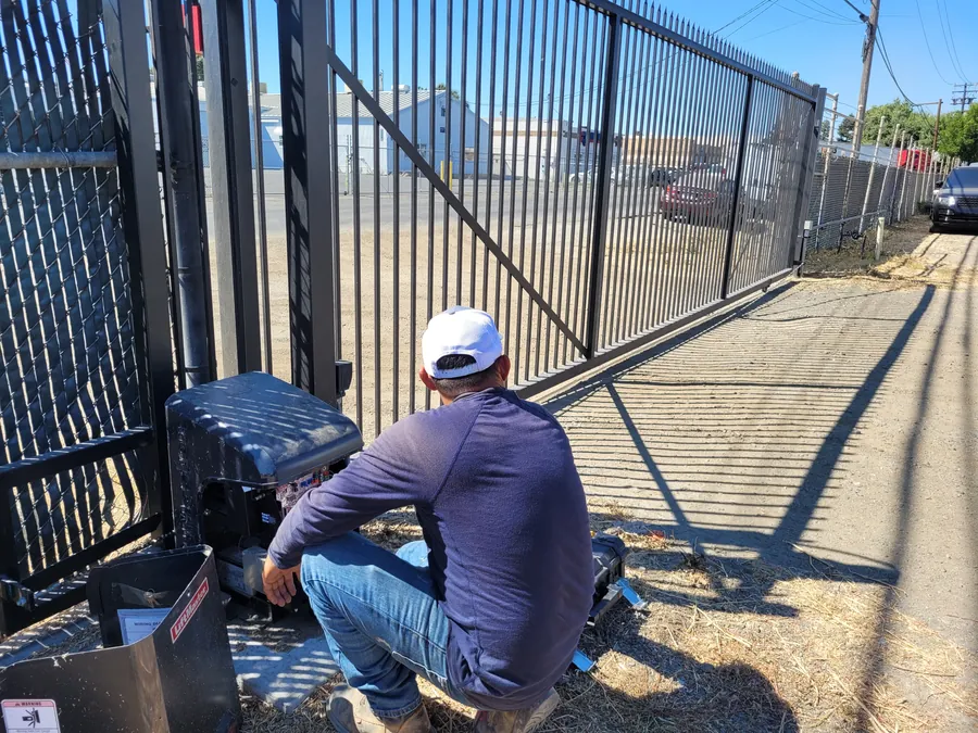 Palmer Fence technician installing a LiftMaster slide gate operator on a commercial iron gate in Sacramento