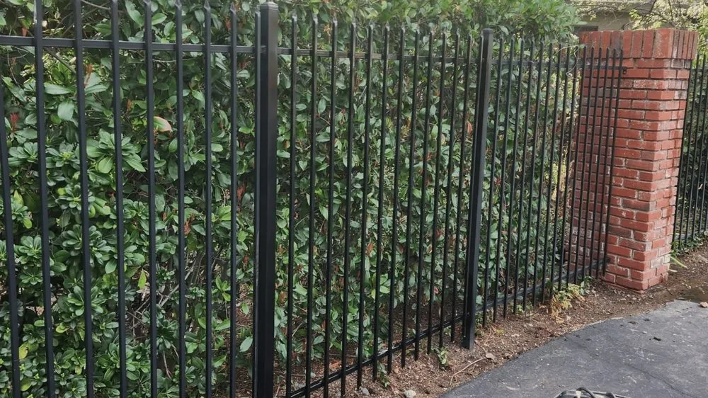 Black ornamental iron fence tied into a brick pillar, installed by Palmer Fence in the Sacramento area