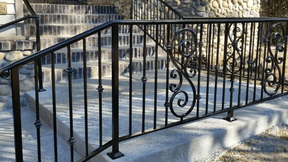 Black ornamental iron stair railing with scrollwork, built by Palmer Fence near Sacramento
