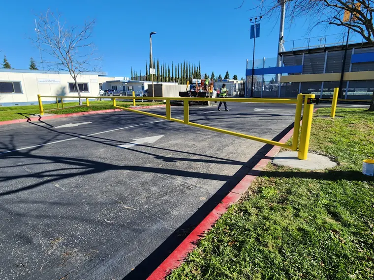 Yellow steel barrier swing gate at a school district parking lot in Sacramento, built by Palmer Fence
