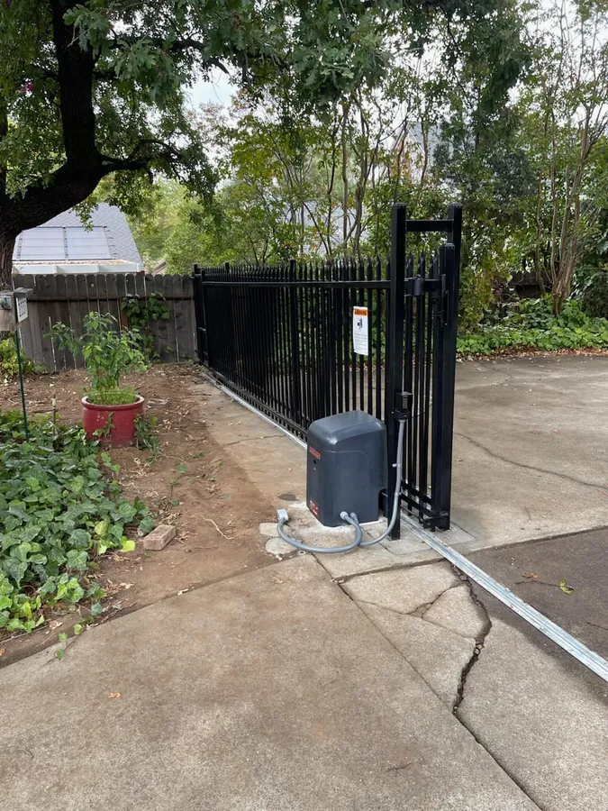 New commercial slide gate operator installed on a concrete pad beside an iron gate by Palmer Fence in Sacramento