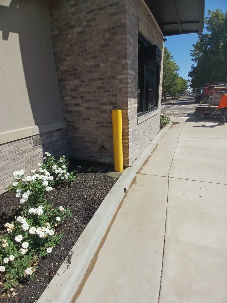 Yellow steel protective bollard guarding a storefront corner in the Sacramento area, installed by Palmer Fence