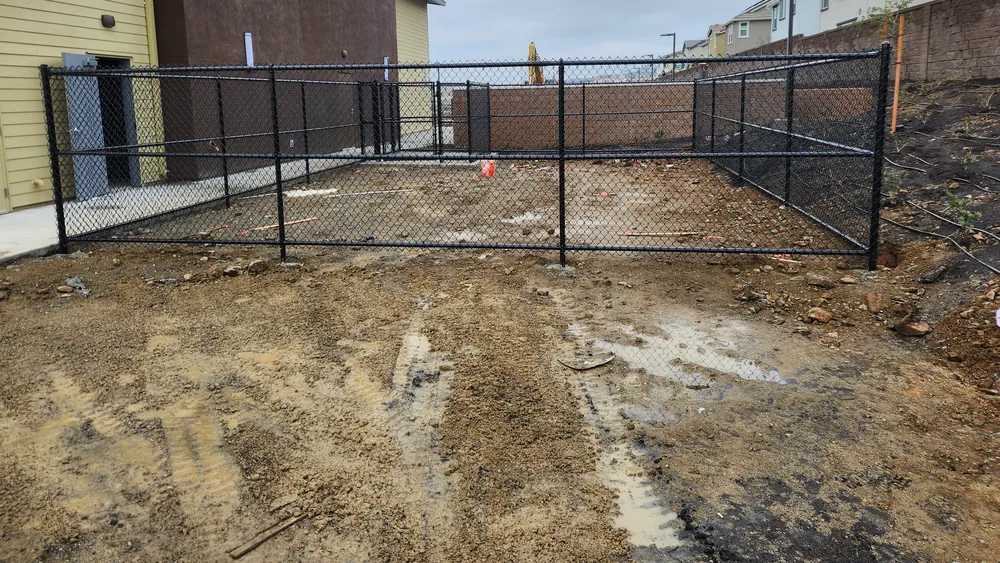 Black vinyl-coated commercial chain link enclosure with gates at a new building site, installed by Palmer Fence
