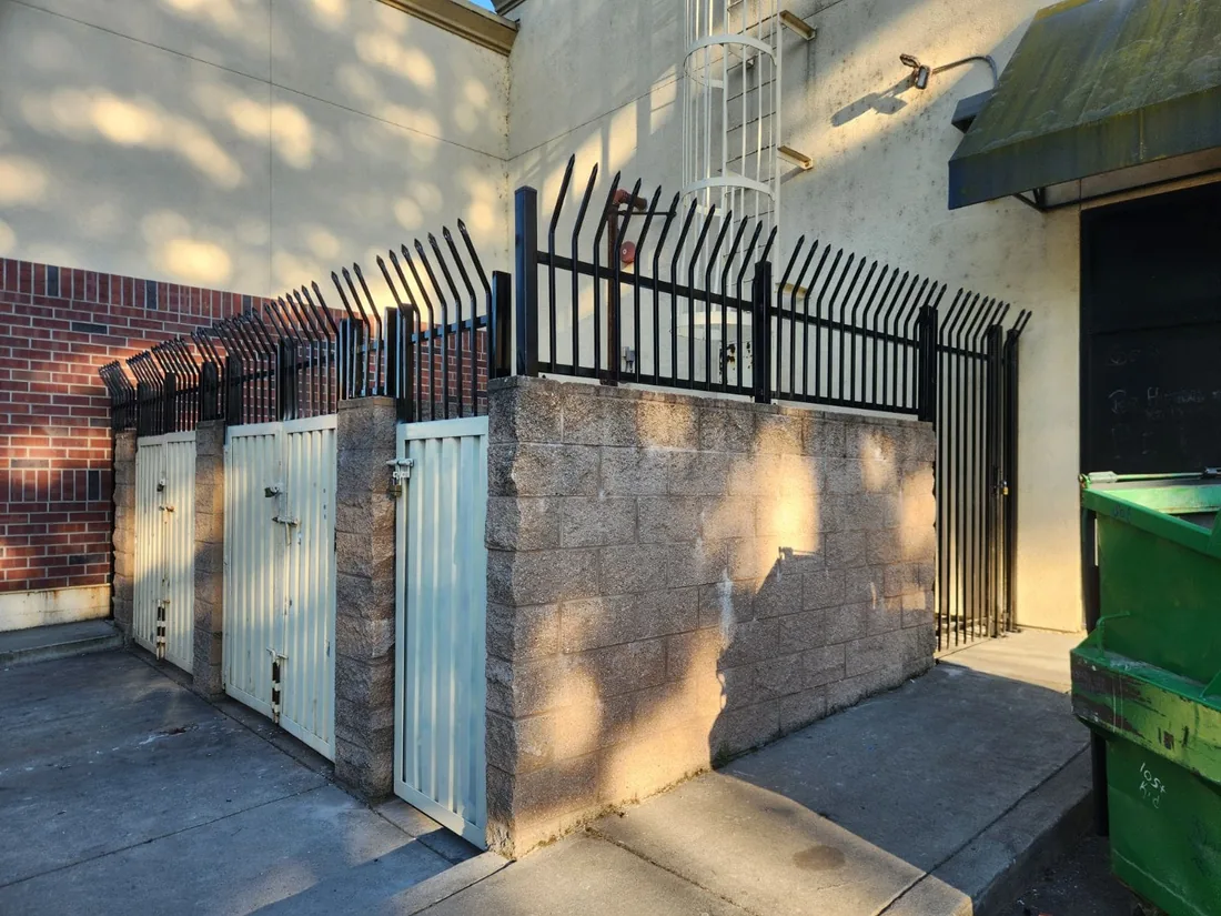 The same enclosure after Palmer Fence added a spear-top iron fence on top of the block wall