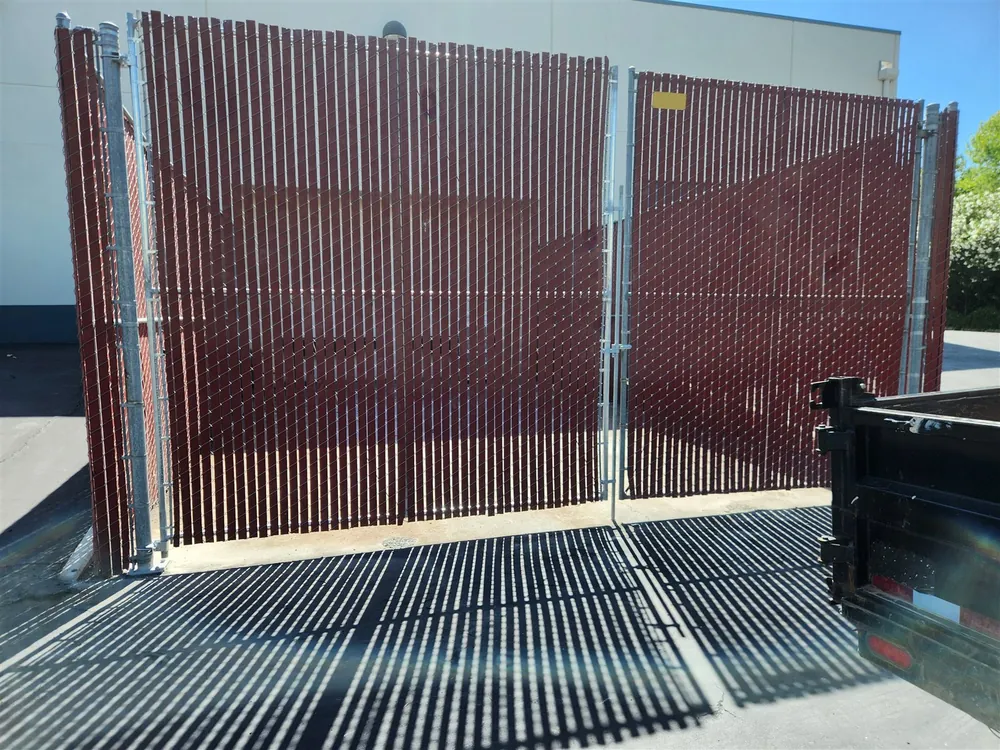 Chain link double gates filled with maroon privacy slats at a commercial building, built by Palmer Fence