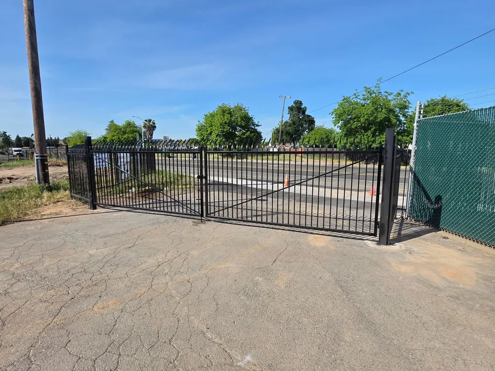 Black double swing iron gate closed across a commercial driveway in Sacramento, built by Palmer Fence