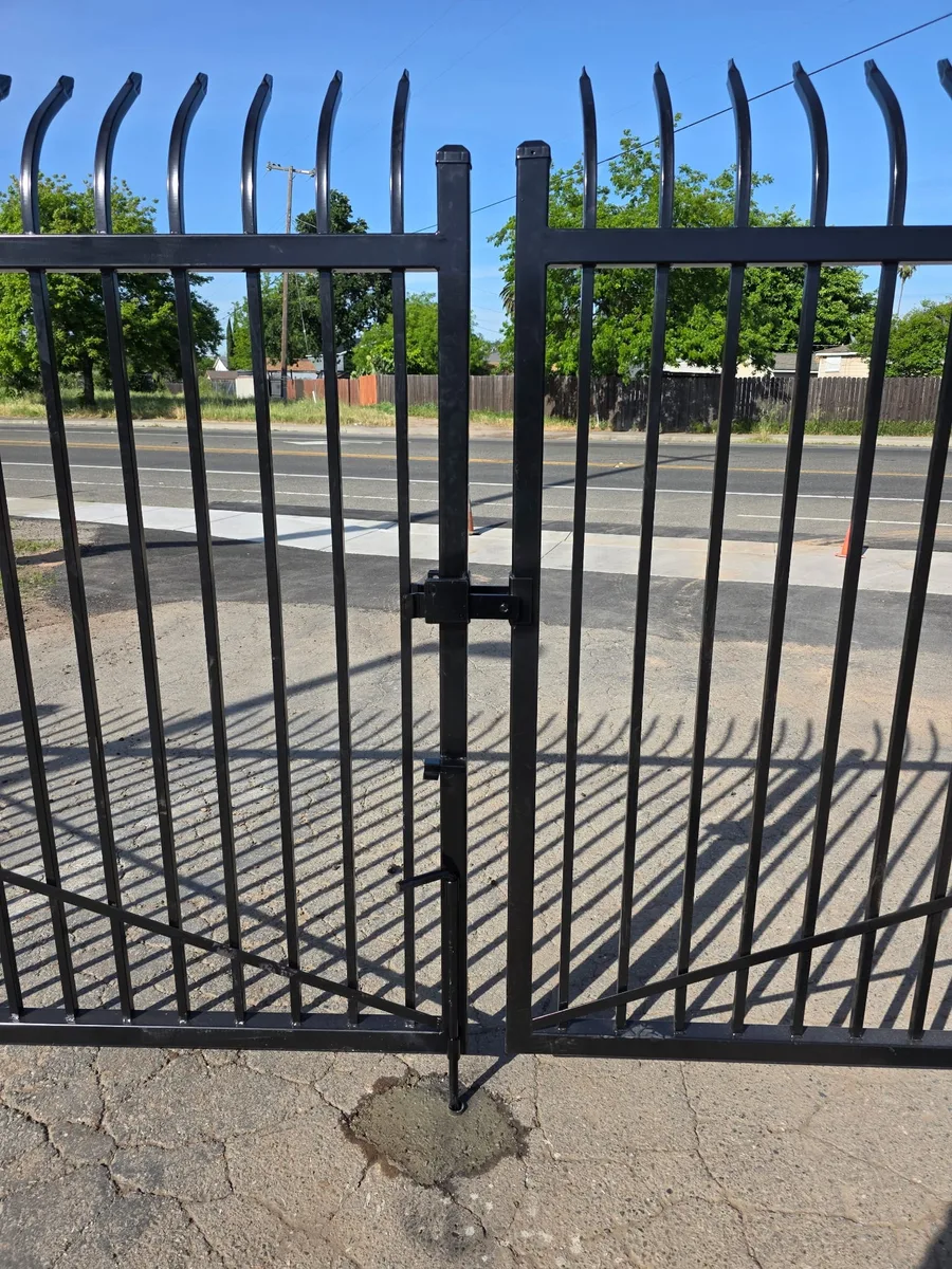 Black double swing iron gate with a center latch and drop rod set into the driveway, built by Palmer Fence in Sacramento
