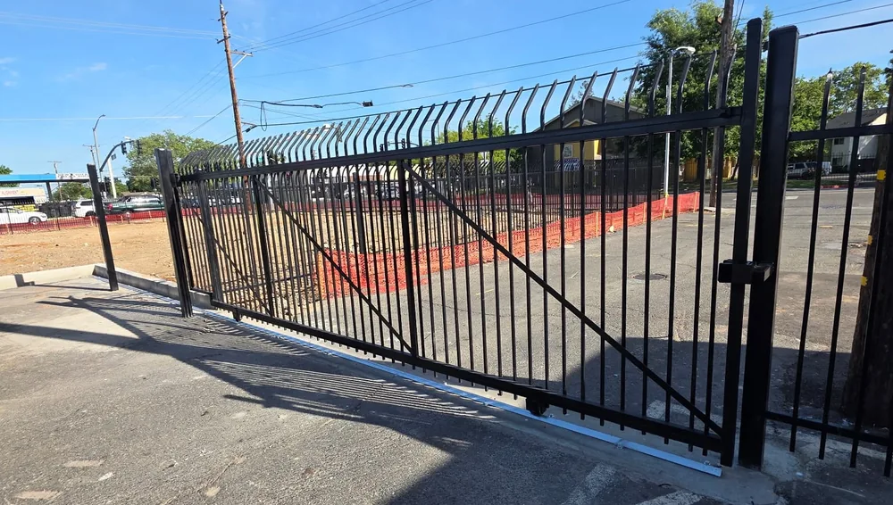 Black rolling gate on its ground track alongside a commercial fence line, built by Palmer Fence in Sacramento