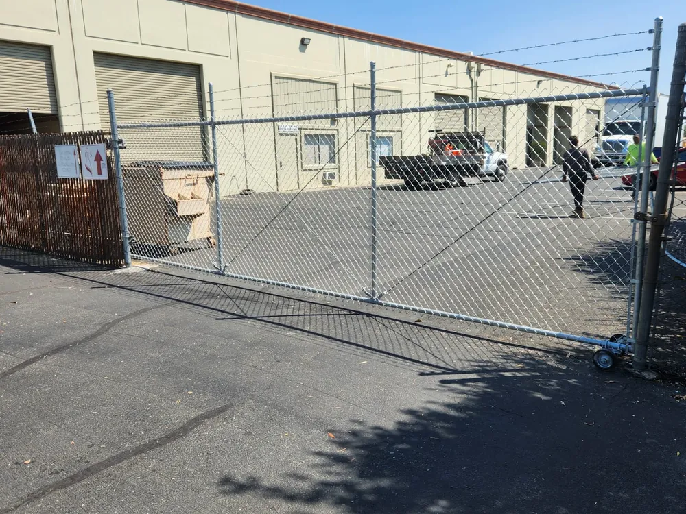 Galvanized chain link fence and rolling gate with barbed wire securing a warehouse yard, built by Palmer Fence
