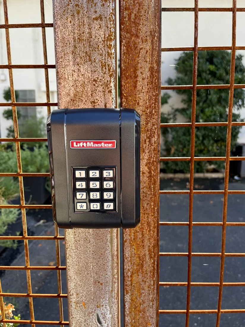 LiftMaster keypad mounted on a steel mesh gate post at a commercial entrance, installed by Palmer Fence