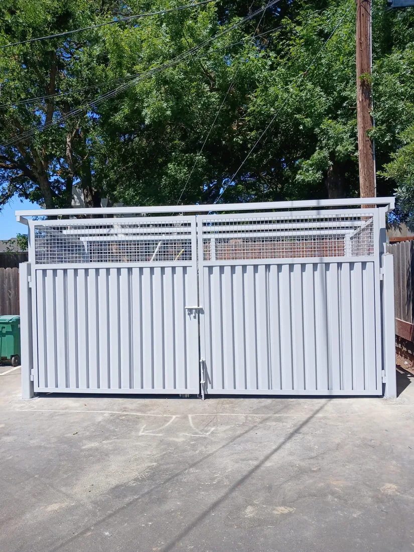 Metal dumpster enclosure gates with a welded mesh panel above, built by Palmer Fence