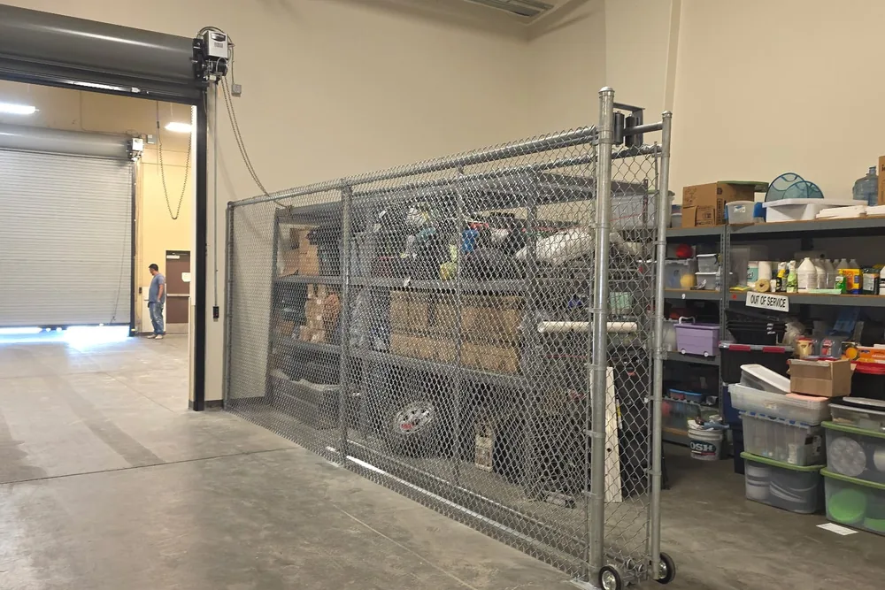 Galvanized chain link rolling gate on wheels securing a storage area inside a warehouse, built by Palmer Fence