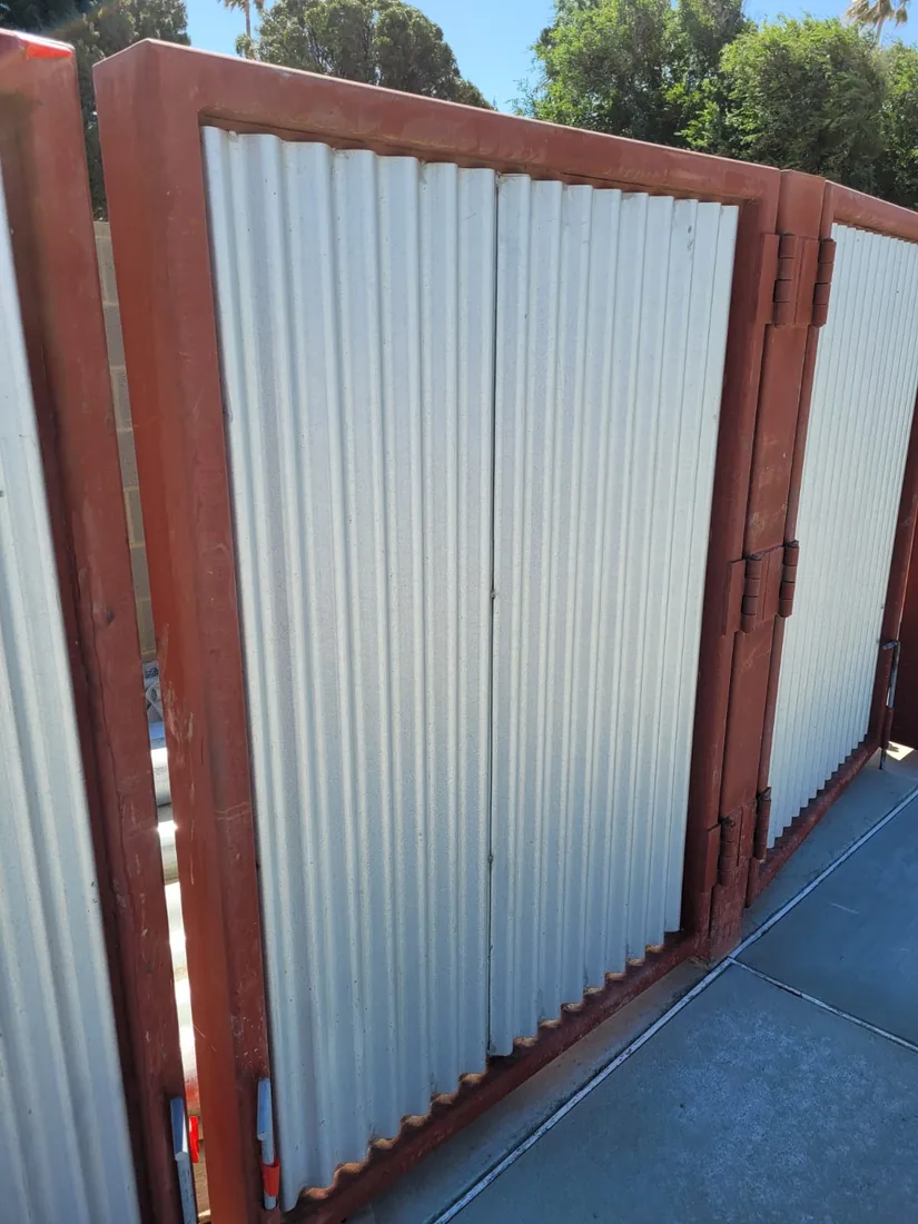 White corrugated metal dumpster enclosure gates in a steel frame, built by Palmer Fence