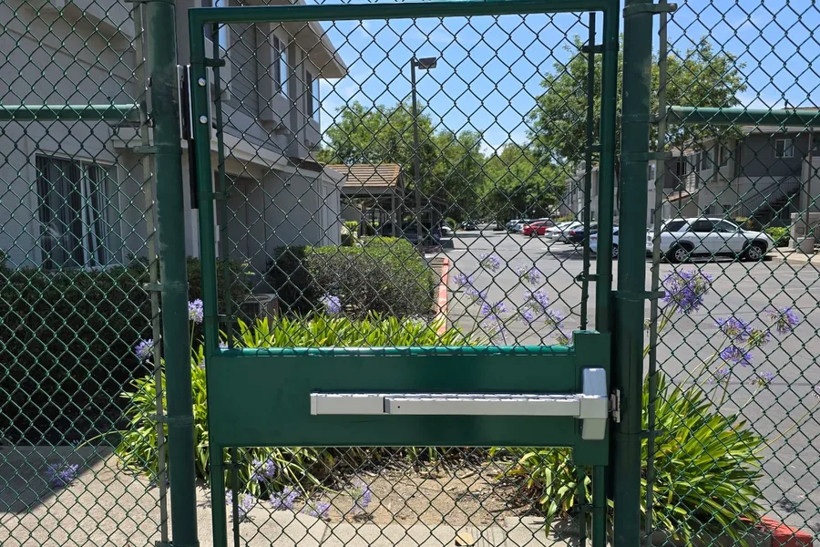 Green chain link pedestrian gate with a panic bar