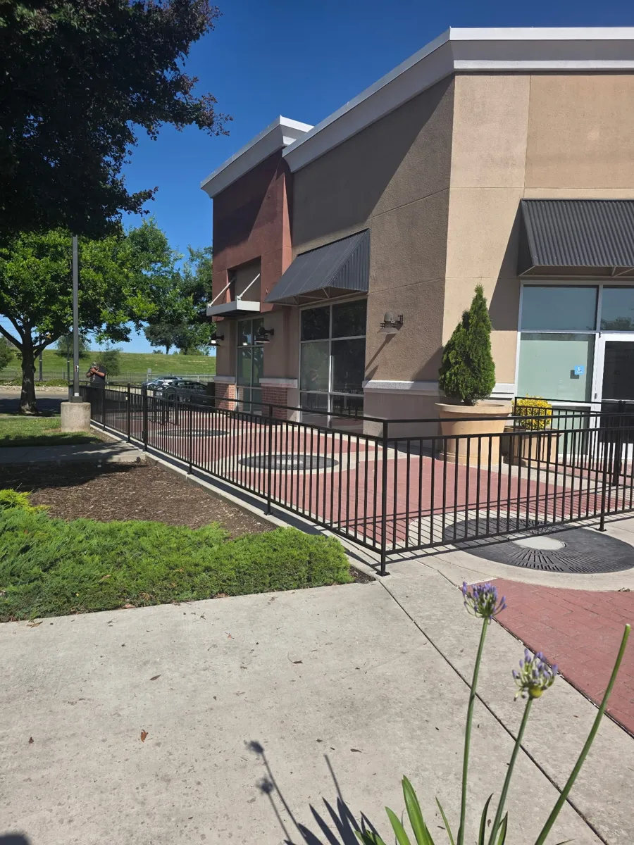 Black steel railing around a retail center plaza, built by Palmer Fence