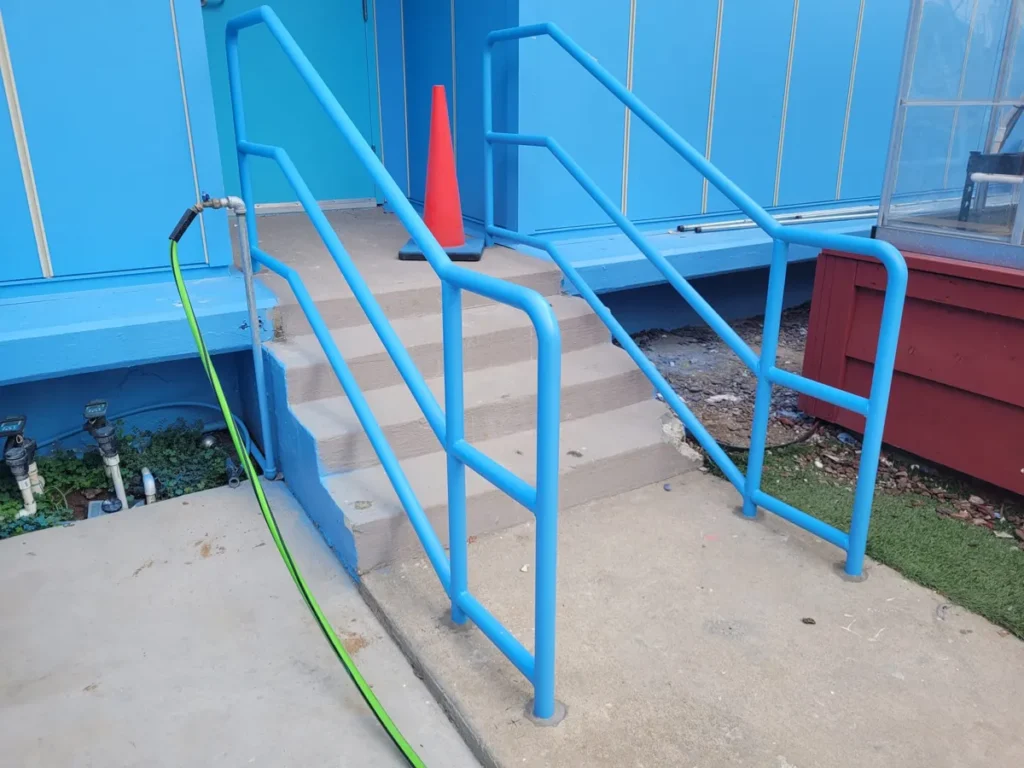 Blue steel handrails core-set at the bottom of concrete steps