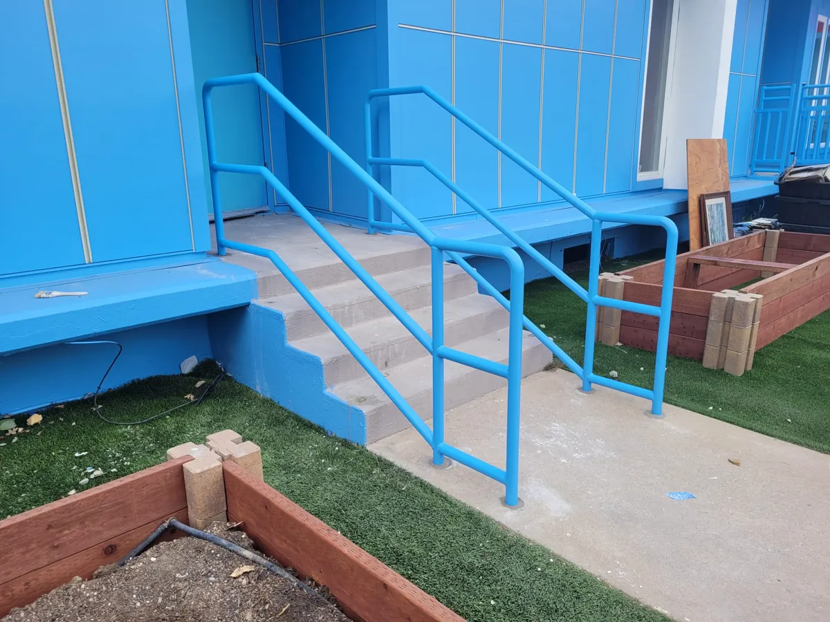 Steel handrails on both sides of an exterior commercial stair, built by Palmer Fence