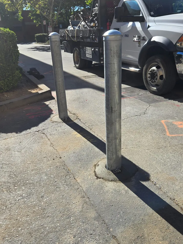 Base of a galvanized steel bollard where it meets the ground, with a concrete collar